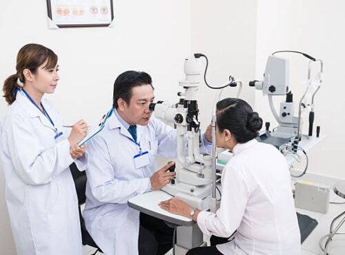Mature doctor and his assistant checking up female patient Mature doctor and his assistant checking up female patient